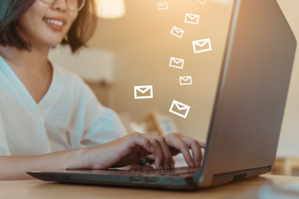 A person using a laptop with digital email icons above suggests an email marketing strategy for customer retention.