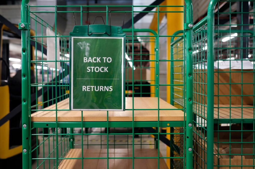 A 'Back to Stock Returns' sign on a warehouse cart, indicating an organized system for processing returns.