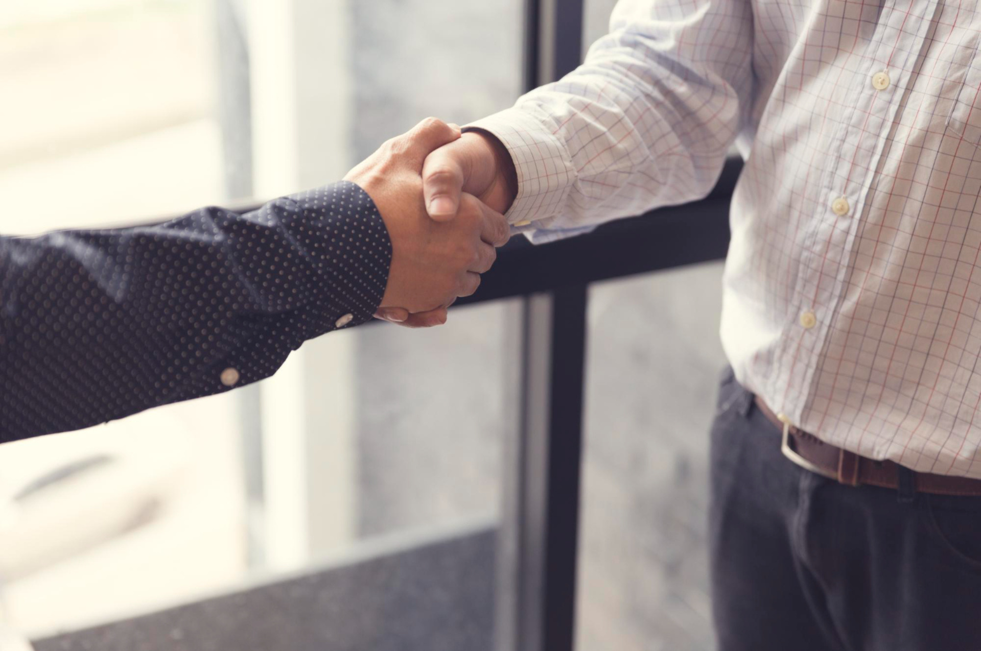 Image of two professionals shaking hands in a corporate setting, symbolizing the establishment of a partnership or agreement, likely between an ecommerce business and a fulfillment service provider.